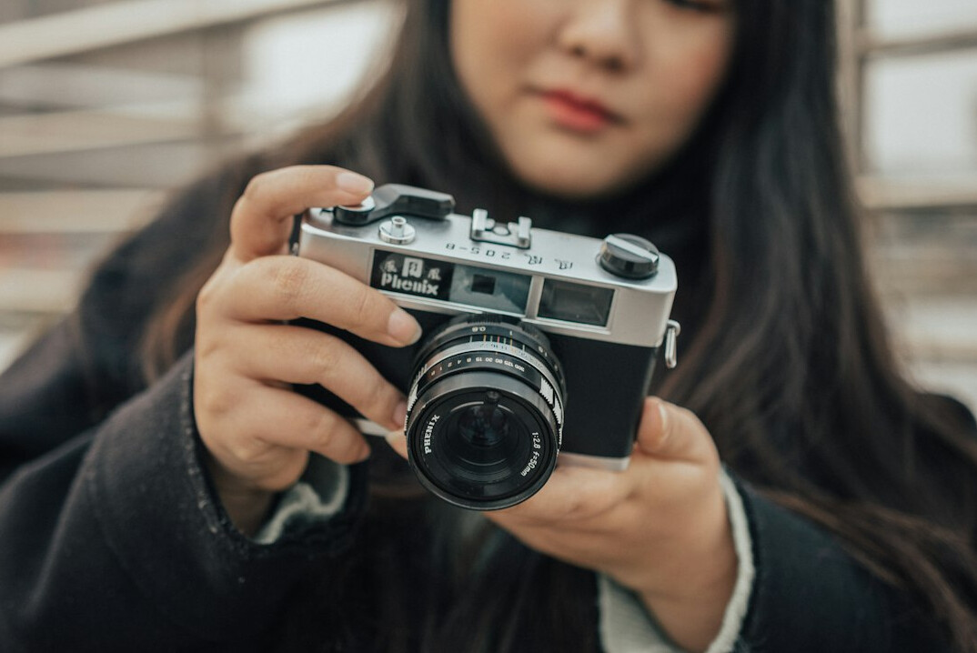 Young female photojournalist holding a film camera